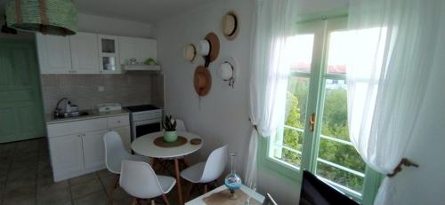 une cuisine avec une table et des chaises ainsi qu'une fenêtre dans l'établissement Paperboat apartment, à Afytos