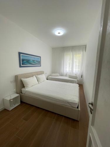 ein weißes Schlafzimmer mit einem Bett und einem Fenster in der Unterkunft Esperia 1 Piscina e Parcheggio in Caorle