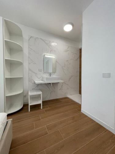 ein Badezimmer mit Waschbecken und einer weißen Wand in der Unterkunft Esperia 1 Piscina e Parcheggio in Caorle