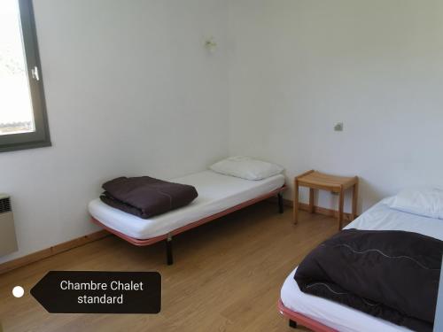 a room with two beds and a small table at Le Pré Martin, gîte de chalets in Annot