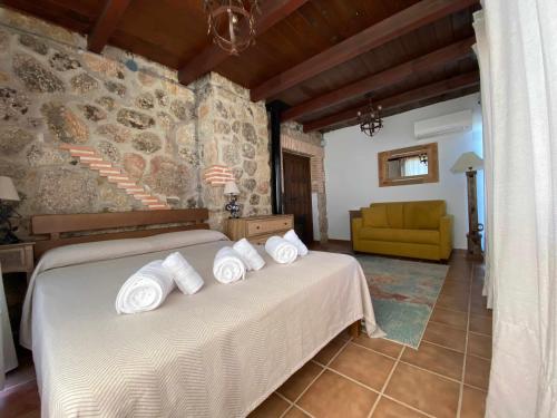 una camera da letto con un letto e asciugamani bianchi di Casa Rural Olivar de Gredos Entorno privilegiado con vistas de ensueño ad Arenas de San Pedro