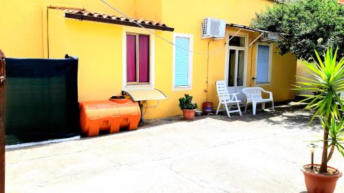 uma casa amarela com cadeiras e um pátio em Mare&Monti II em Telti