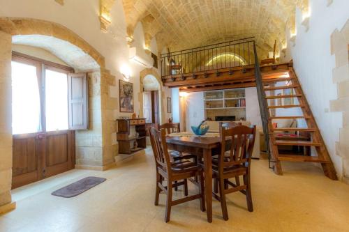 ein Esszimmer mit einem Tisch und einer Wendeltreppe in der Unterkunft San Domenico Suite in Martano