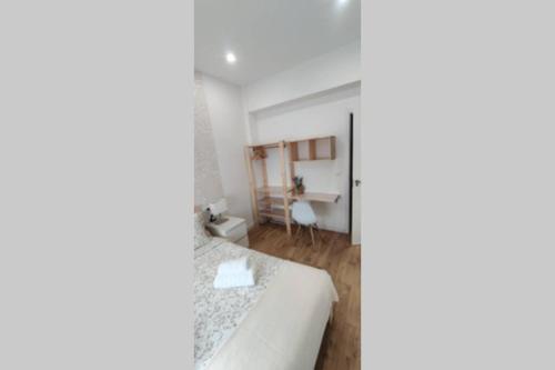 Cette chambre blanche comprend un lit et un bureau. dans l'établissement Xátiva Home, Loft Center, à Xàtiva