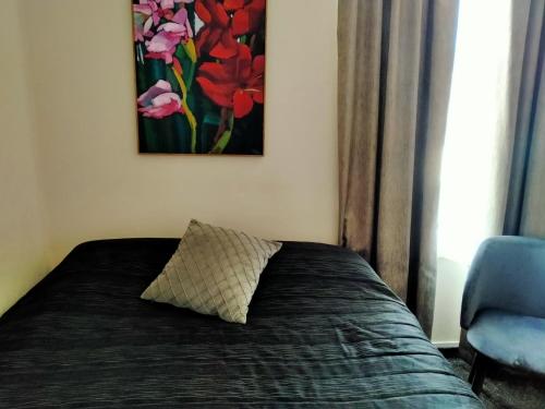 a bed with a pillow and a painting on the wall at Masonic Hotel in Palmerston North