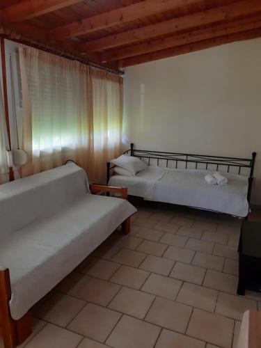 a bedroom with two beds and a window and a tiled floor at Studios Lainis in Toroni