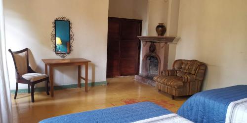 a bedroom with a bed and a chair and a fireplace at Hotel Sautto in San Miguel de Allende