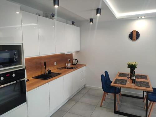 a kitchen with white cabinets and a table with blue chairs at Haven Apart 2 in Jelenia Góra