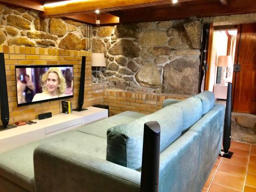 a living room with a couch and a tv at Pedacinho de Mundo Douro in Passinhos de Cima