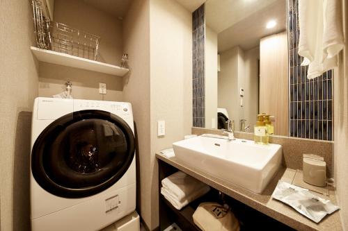uma casa de banho com uma máquina de lavar roupa e um lavatório em MONday Apart Premium UENO OKACHIMACHI em Tóquio