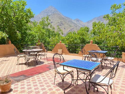 un patio con tavoli e sedie con montagne sullo sfondo di Riad Atlas Garden a Imlil