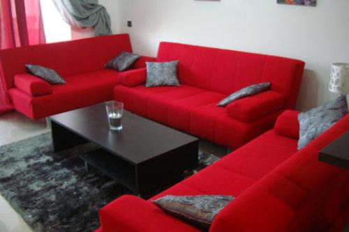 アシラにあるAppartement de luxeのリビングルーム(赤いソファ、テーブル付)