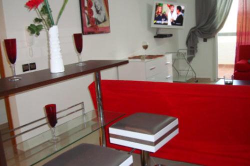 a red chair and a glass table with two wine glasses at Appartement de luxe in Asilah