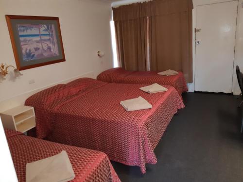 塔姆沃思的住宿－克魯尼歐汽車旅館，两张位于酒店客房的床铺,配有红色床单