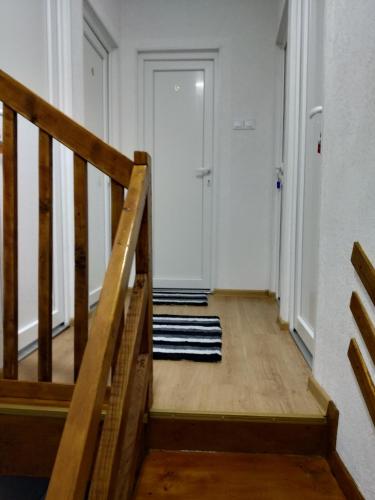a hallway with a wooden staircase and a white door at Guest House RG in Žabljak