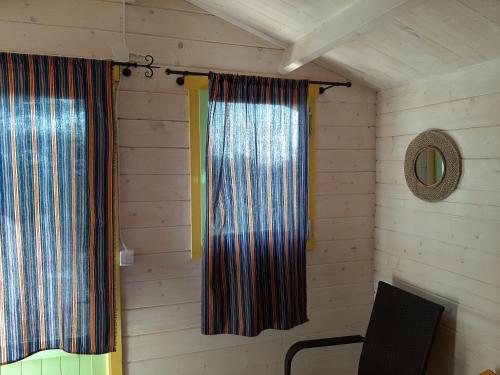 a room with two curtains and a chair and a mirror at Kadakasuitsu Loodustalu in Saareküla