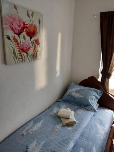 a bed in a bedroom with a painting on the wall at Guest House RG in Žabljak