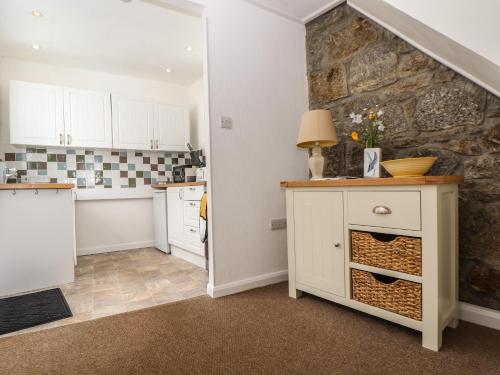 een keuken met witte kasten en een stenen muur bij Lookout Cottage in Penzance