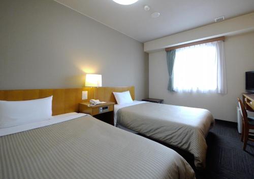 a hotel room with two beds and a window at Hotel Route-Inn Nagaizumi Numazu Inter 1 in Nagaizumi