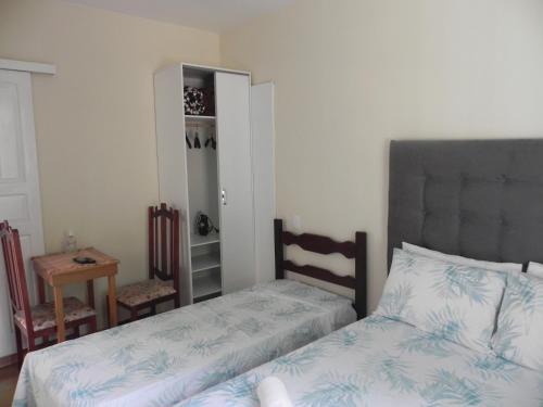 a bedroom with two beds and a table and a mirror at Aconchego Valparaíso in Petrópolis