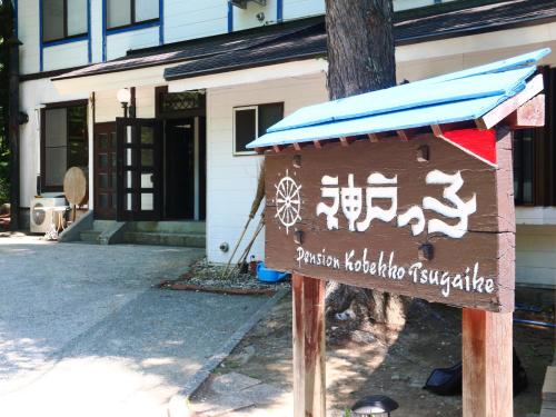a wooden sign in front of a building at Pension Kobekko in Otari