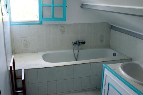 a bathroom with a bath tub and a sink at La porte bleue in Baie-Mahault