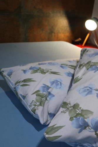 a pillow with blue flowers on it sitting on a bed at Casa com Quarto Simples a 4 KM do aeroporto de São José dos Pinhais in São José dos Pinhais