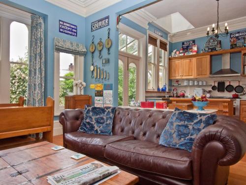 a living room with a brown leather couch in a kitchen at Lilac Rose Boutique Bed and Breakfast in Christchurch