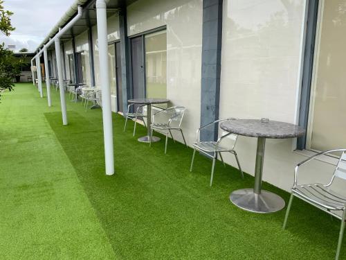 a row of tables and chairs on a balcony with green grass at Top 1 Motel in Rockhampton