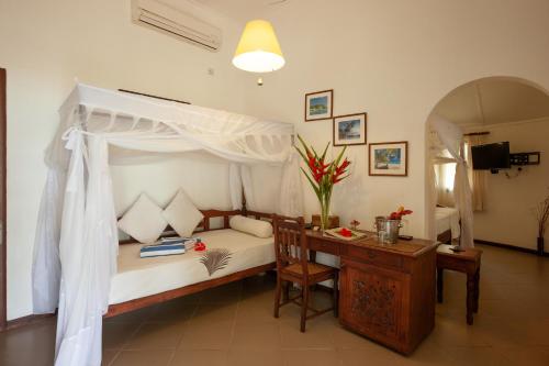 a bedroom with a bed with a desk and a canopy at Hotel Cote d'or Lodge in Baie Sainte Anne