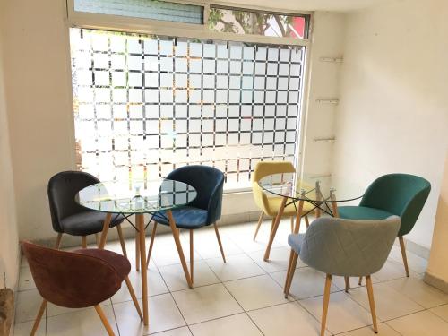 ケレタロにあるCasa Internacional Querétaroの椅子とテーブル、窓が備わる客室です。