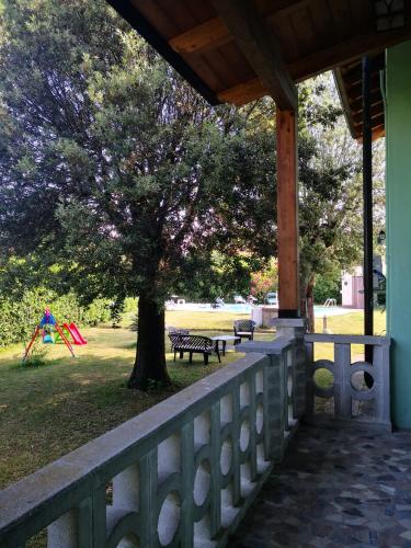 a porch with a tree and a park with a bench at Villa Franco in Orentano