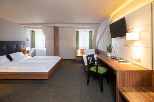 a bedroom with a bed and a desk with a computer at JOESEPP´S HOTEL am Hallhof in Memmingen