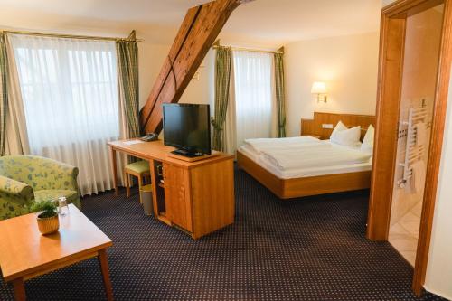 a hotel room with a bed and a television at Landhotel Hirschen in Oberwolfach