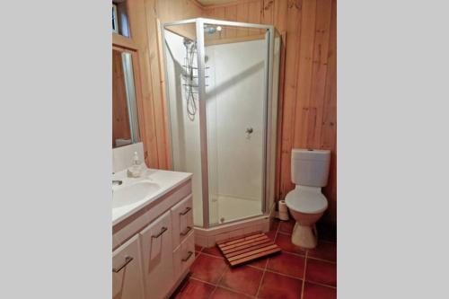 a bathroom with a shower and a sink and a toilet at Native Garden Retreat in Gisborne