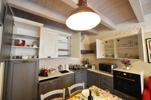 a kitchen with white cabinets and a table and a light at La Beppa - Casa Vacanza in Pontremoli