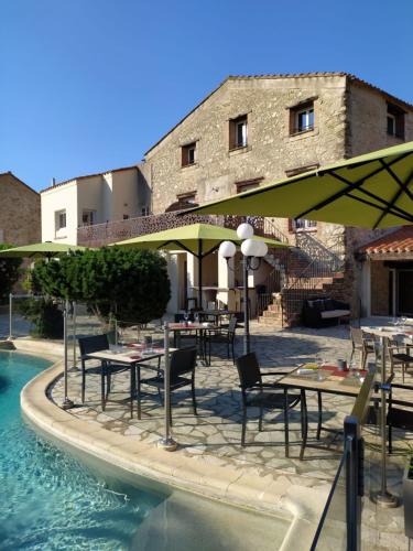 a restaurant with tables and umbrellas next to a pool at Auberge Du Roua in Argelès-sur-Mer