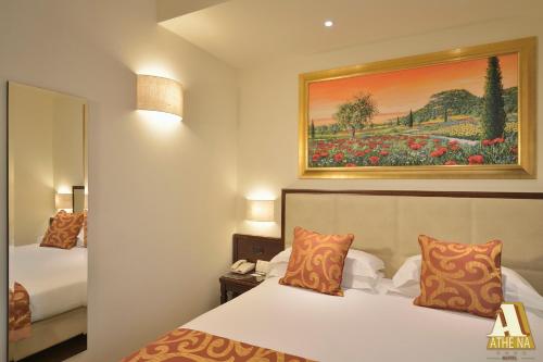 a hotel room with two beds and a painting on the wall at Hotel Athena in Siena
