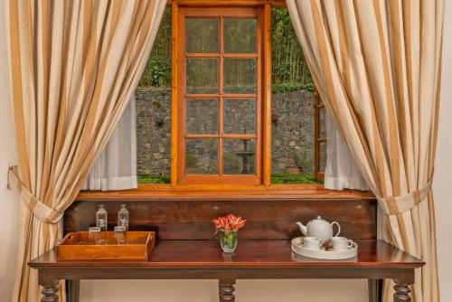 a window with curtains and a table with a bowl of flowers at Jetwing Warwick Gardens, A Luxury Reserve in Nuwara Eliya