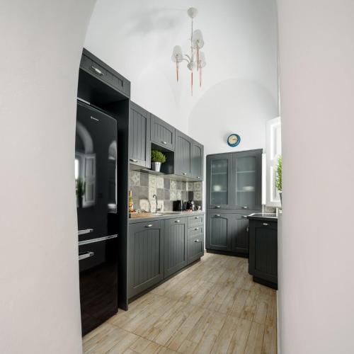 a kitchen with gray cabinets and a black refrigerator at Betty's Home Santorini in Karterados