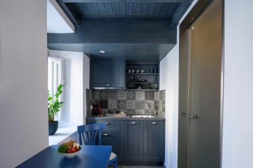 a kitchen with blue cabinets and a blue table at Betty's Home Santorini in Karterados