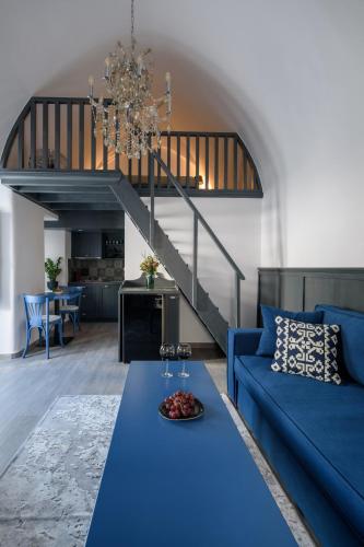 a living room with a blue couch and a staircase at Betty's Home Santorini in Karterados