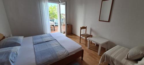 a bedroom with a bed and a chair and a window at Adria Arba Apartments in Rab