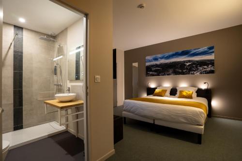 a bedroom with a bed and a shower and a sink at Le Genève in La Bourboule