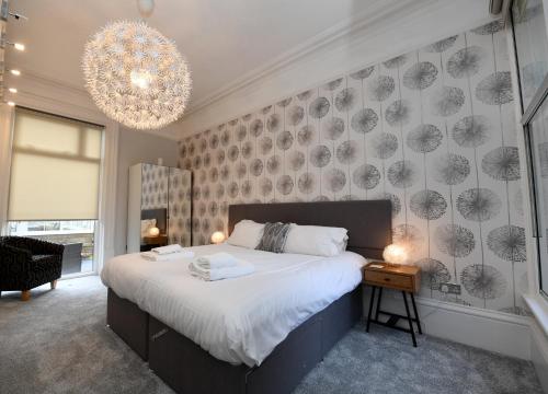 a bedroom with a large bed and a chandelier at Harrogate Self Catering - Mews Suite - Garden in Harrogate