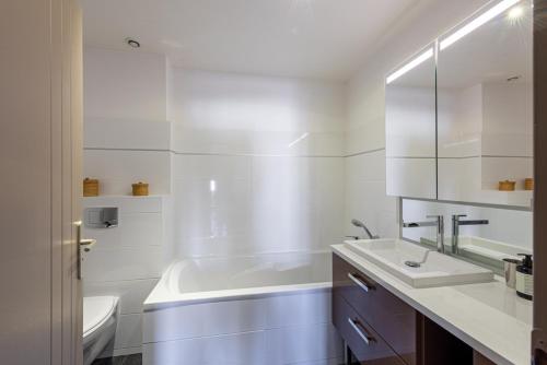 La salle de bains blanche est pourvue d'un lavabo et d'une baignoire. dans l'établissement Le Palais, à Dijon