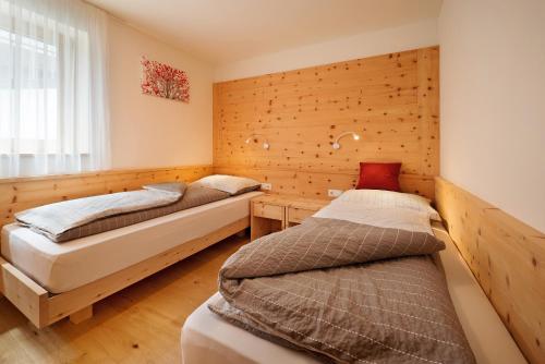 2 letti in una camera con pareti in legno di Teutenhofer Kirsche a Velturno
