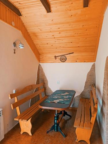 stół i ławka w pokoju z drewnianym sufitem w obiekcie Приватна Садиба Потічок w Sławsku