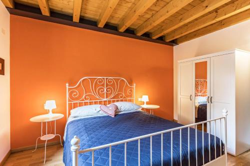 een slaapkamer met een blauw bed en een oranje muur bij Le Pleiadi Merope in Gardone Riviera