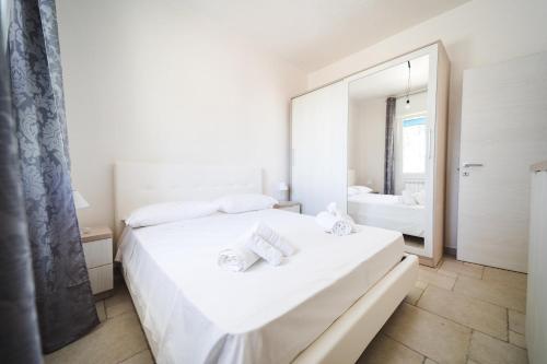 a white bedroom with a large white bed and a mirror at Villetta Giorgia Torre Suda in Torre Suda